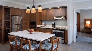 Una cucina moderna con mobili in legno, un frigorifero in acciaio inossidabile, forno integrato e zona pranzo con tavolo bianco e sedie a fantasia.