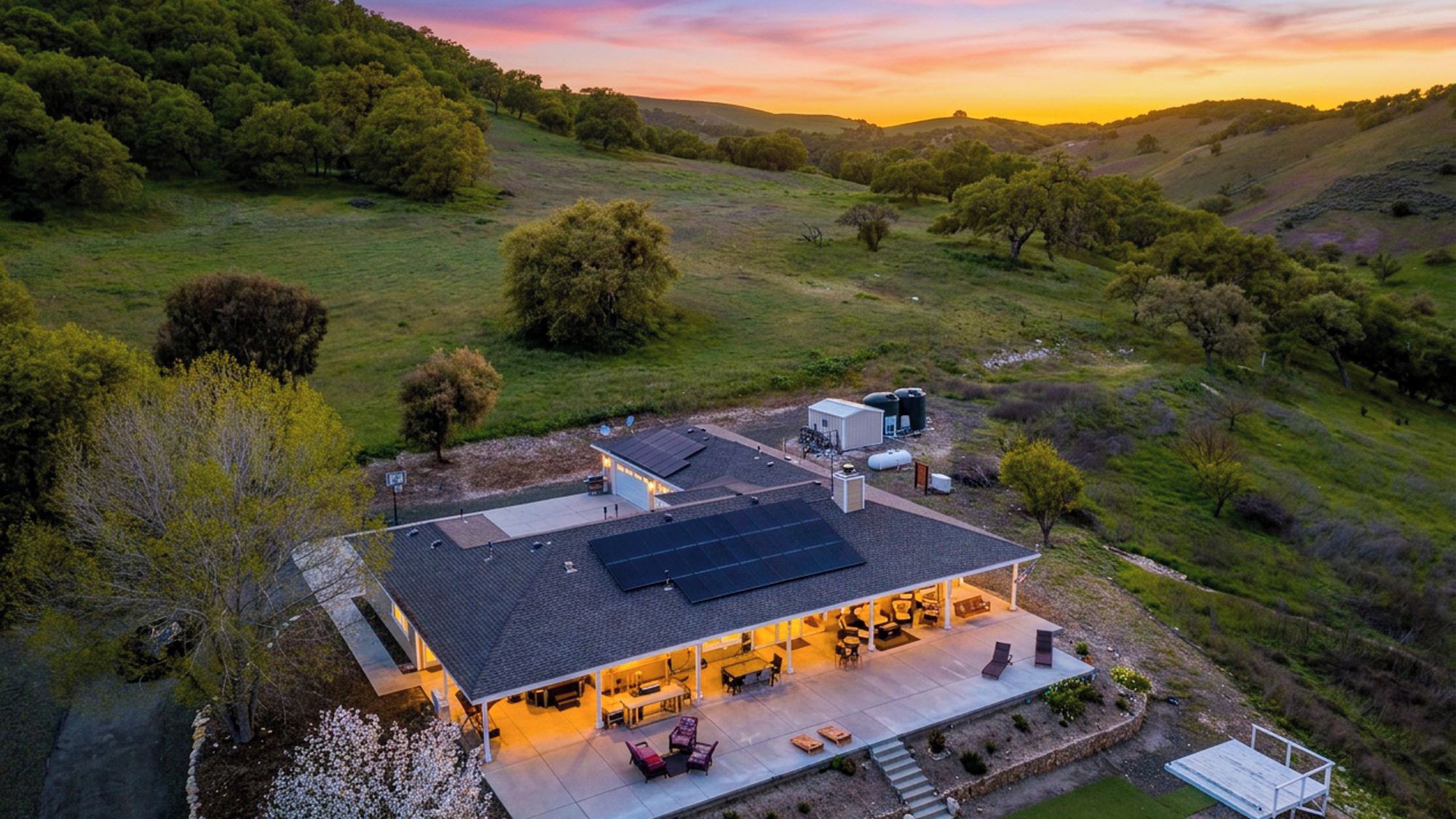 A modern house with a large patio, solar panels, and a view of the surrounding countryside.