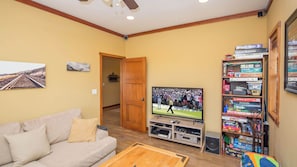 Una sala de estar con televisión, estantería y sofá.