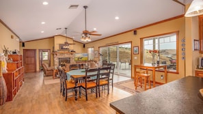 A spacious living area with a fireplace, dining table, and comfortable seating. - The J's Nest by Avantstay Hot Tub + BBQ + Lawn Games Panoramic Lake + Oak Hill Views (Bradley)