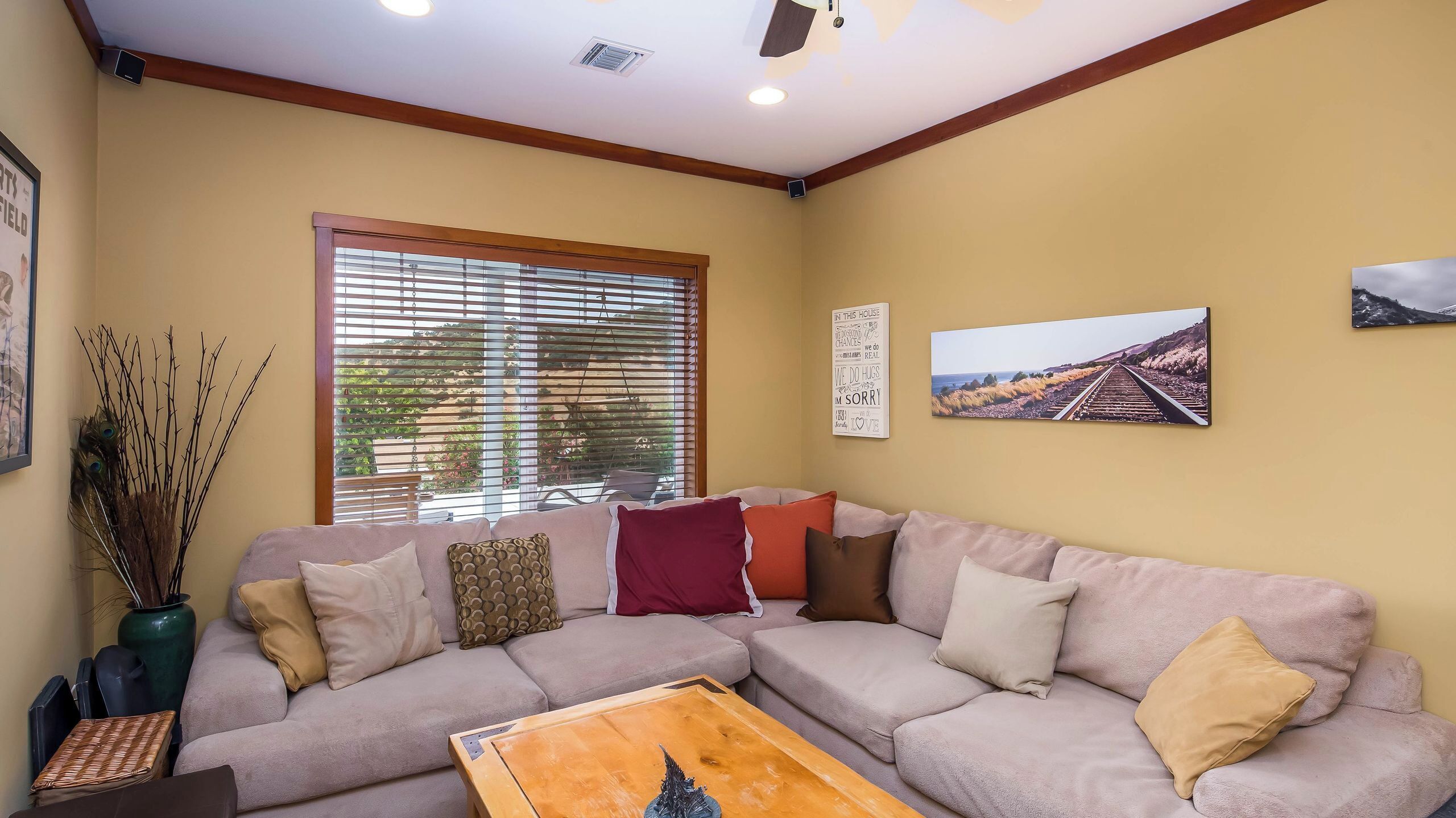 A living room with a beige sofa, a wooden coffee table, and a window with blinds.