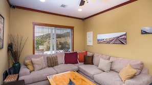 A living room with a beige sofa, a wooden coffee table, and a window with blinds.