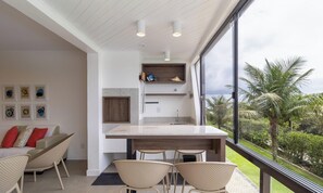 A modern kitchen with a large island, built-in shelves, and a view of the outdoors. - Charming Apartment With Barbecue Por0101 (Florianópolis)