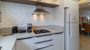 Eine moderne Küche mit weißen Schränken, einem Gasherd, einem Backofen und einem Kühlschrank.