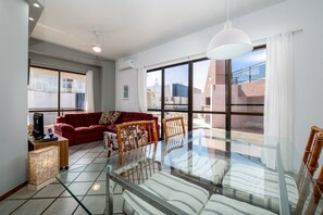 Ein modernes Wohnzimmer mit einem Glastisch, einem roten Sofa und Korbstühlen.