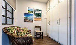 A hallway with a wicker sofa, a wooden chair, and a wardrobe. There are three framed pictures on the wall. - Apto With Panoramic View of the sea Front Por204 (Florianópolis)