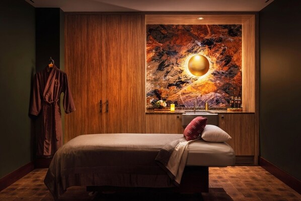 A bedroom with a bed, a wooden wardrobe, and a wall-mounted artwork.