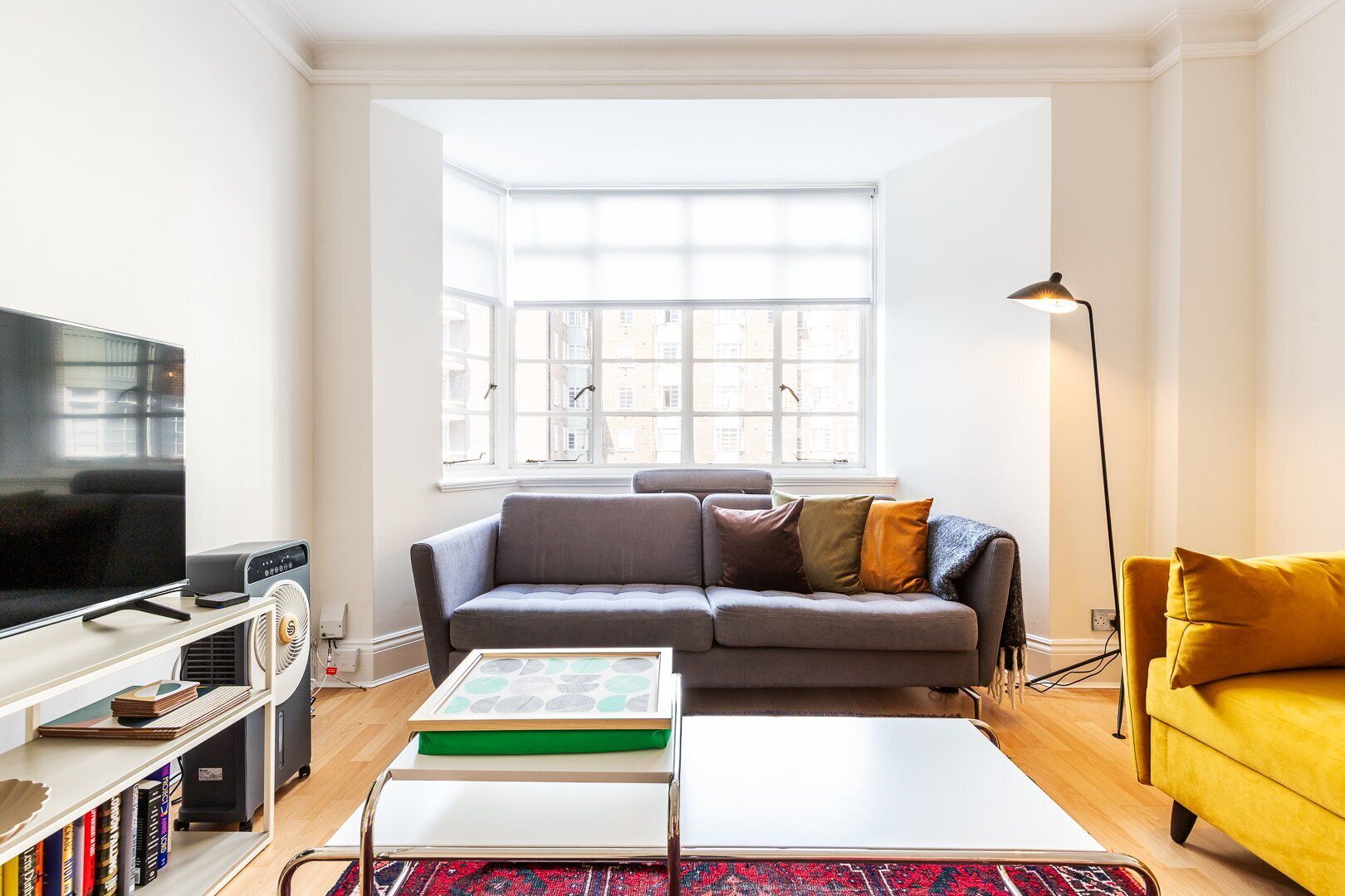 Een woonkamer met een televisie, bank en een gele fauteuil.
