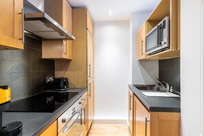 Eine kleine Küche mit Holzausstattung, einer Mikrowelle, einem Toaster und einem Spülbecken.