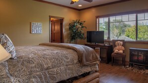 A bedroom with a bed, a television, a teddy bear, a fireplace, and a window with blinds. - The J's Nest Deluxe by Avantstay Sleeps 18 Hot Tub + Game Room Paso Robles (Bradley)