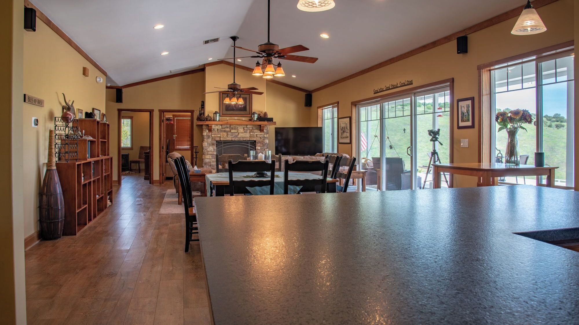 A spacious kitchen with a large island, wooden cabinetry, and a stone fireplace.