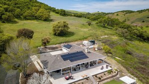 A house with a covered patio, solar panels, and a view of the surrounding hills. - The J's Nest Deluxe by Avantstay Sleeps 18 Hot Tub + Game Room Paso Robles (Bradley)