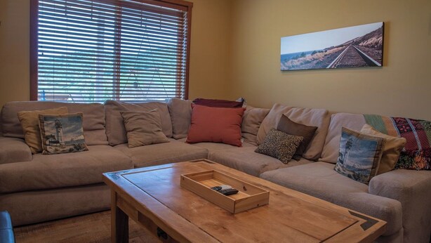 A living room with a beige sofa, a wooden coffee table, and a painting on the wall. - The J's Nest Deluxe by Avantstay Sleeps 18 Hot Tub + Game Room Paso Robles (Bradley)
