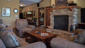 A living room with a stone fireplace, leather sofas, a coffee table, and a television. - The J's Nest Deluxe by Avantstay Sleeps 18 Hot Tub + Game Room Paso Robles (Bradley)