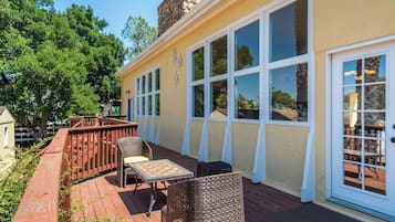 A covered patio with outdoor furniture, a wooden deck, and a stone wall.