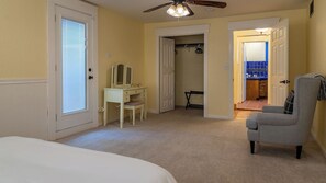 A bedroom with a bed, a desk with a chair, a ceiling fan, and a door leading to a bathroom. - Union Road Schoolhouse by Avantstay Sleeps 10 + Pizza Oven + Spa + Firepit Historic 1923 Estate (Paso Robles)