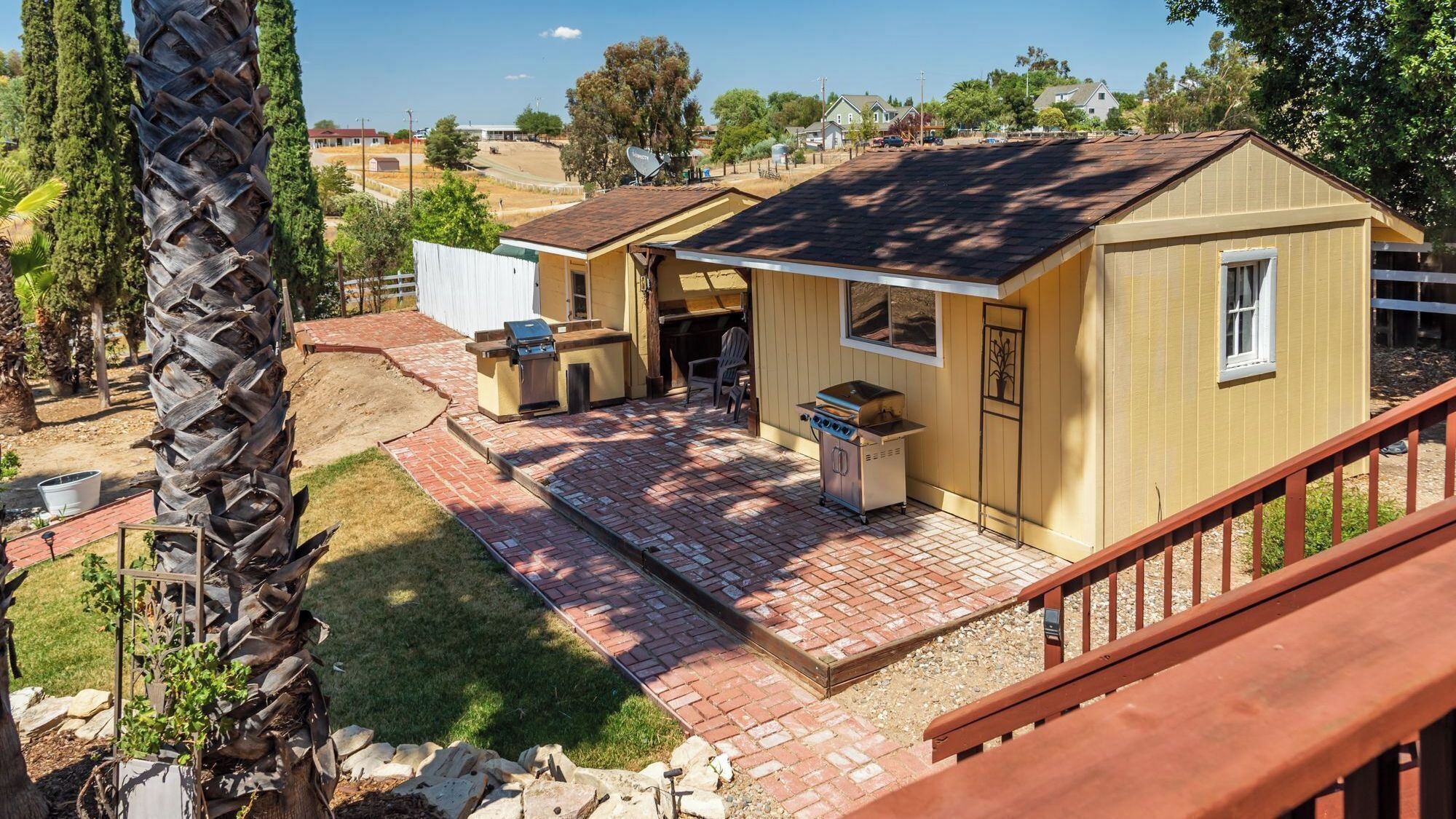 A residential property with a patio area, a barbecue grill, and a small shed.