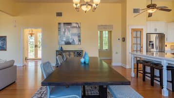 A spacious dining area with a long table, chairs, and a chandelier.