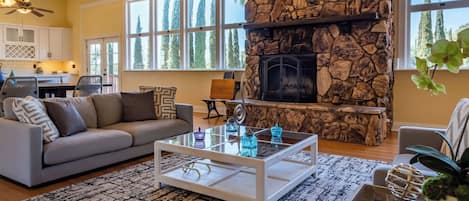 A living room with a stone fireplace, large windows, a sofa, and a coffee table.