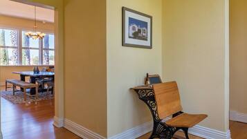 A dining area with a table and chairs, a framed picture on the wall, and a hallway leading to another room.