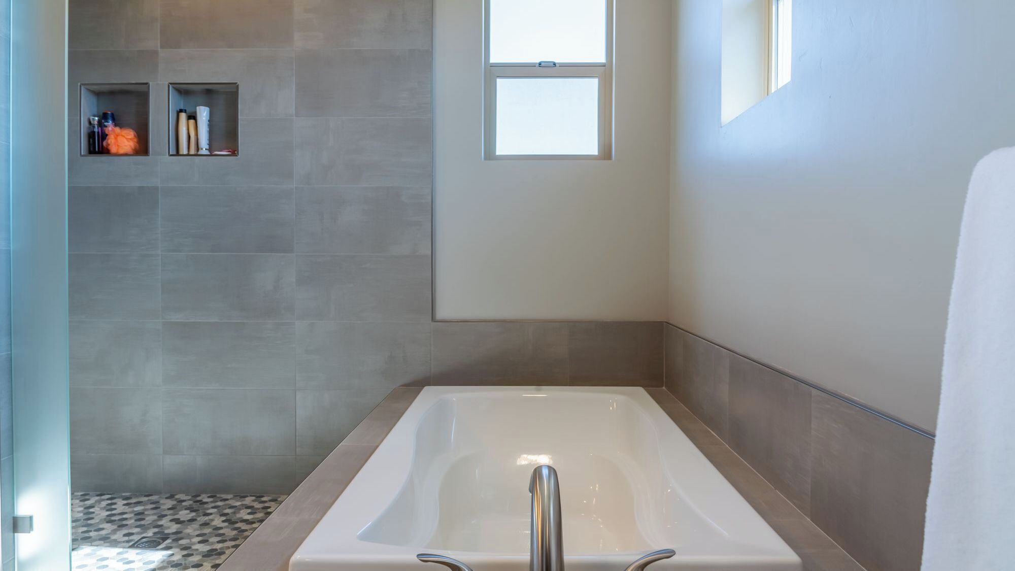 A modern bathroom with a freestanding bathtub, tiled walls, and a shower area.