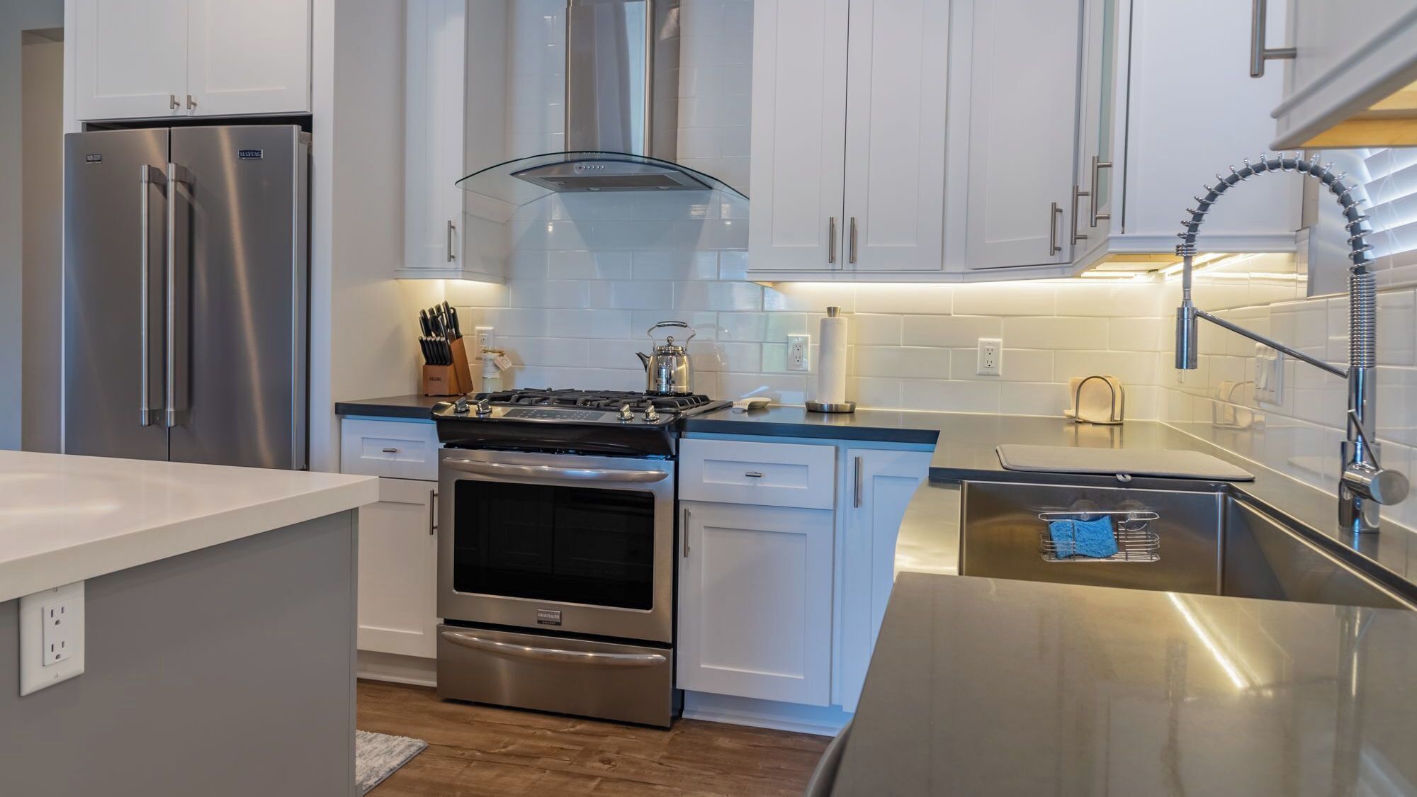 Una cocina moderna con electrodomésticos de acero inoxidable, armarios blancos y horno empotrado.