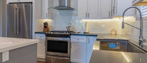 Una cocina moderna con electrodomésticos de acero inoxidable, armarios blancos y horno empotrado.