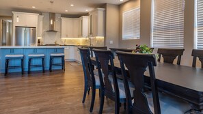 Una cocina moderna con una isla central, taburetes de bar y una mesa de comedor con sillas.