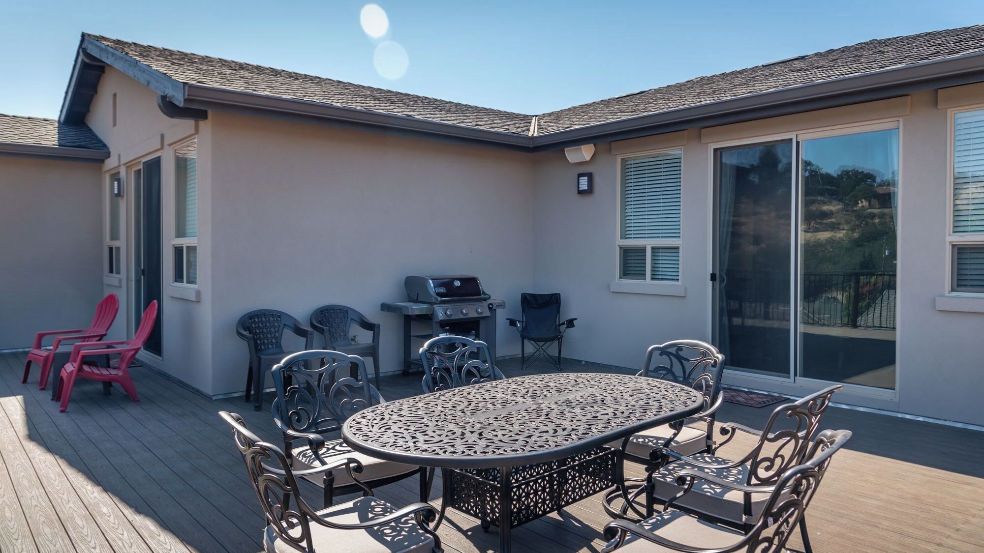 A covered patio with a round table and chairs, a grill, and a sliding glass door.