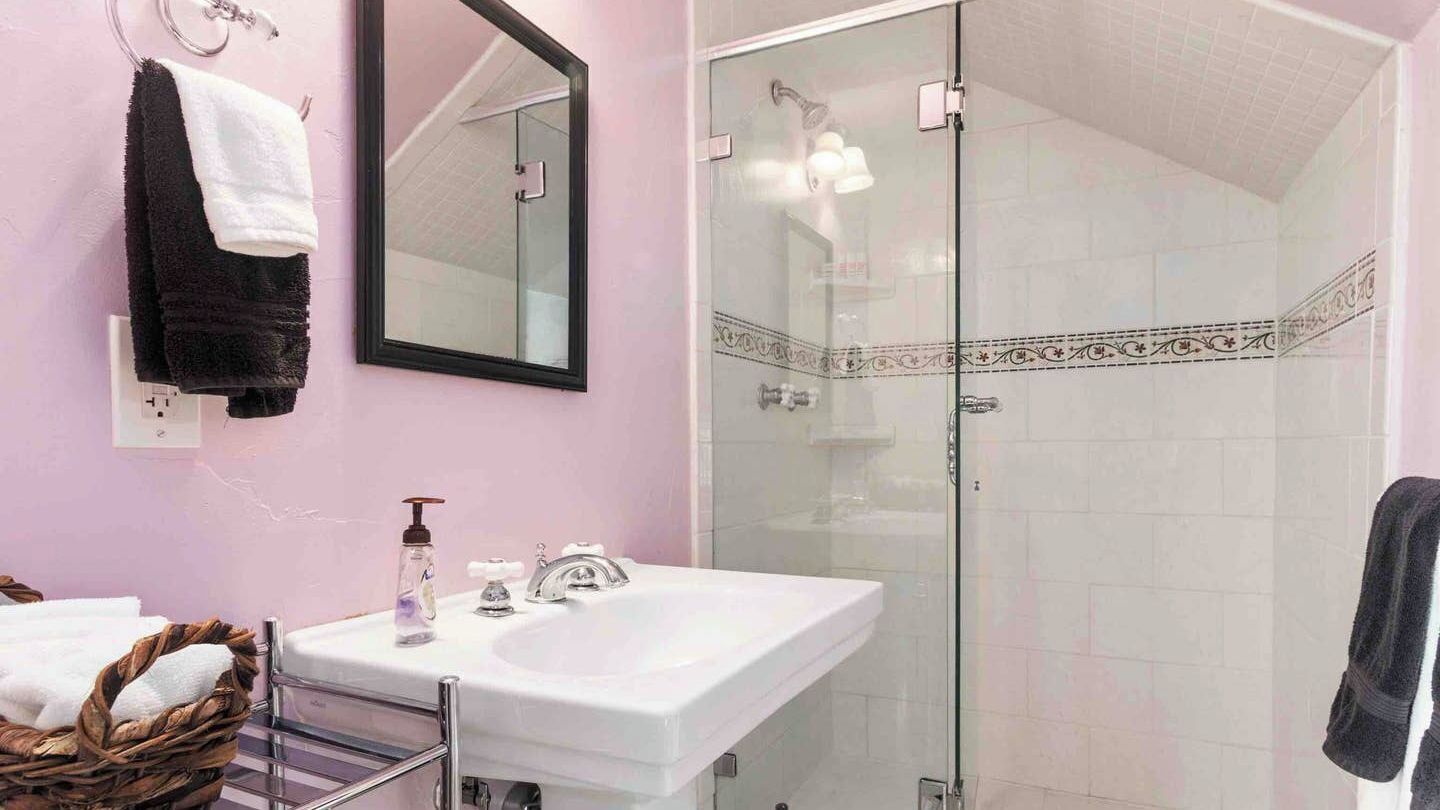 A bathroom with a white sink, a glass shower enclosure, and a mirror.
