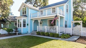 Ein zweistöckiges Haus mit Balkon, weißem Zaun und einer US-amerikanischen Flagge.