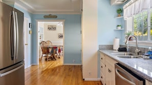 A kitchen with a stainless steel refrigerator, a granite countertop, a sink, and a dining area with a table and chairs. - Vacations on Vine by Avantstay BBQ Yard + Patio Paso Robles Wine Country (Paso Robles)