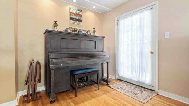 A room with a piano, a bench, a rug, and a door with curtains. - Vacations on Vine by Avantstay BBQ Yard + Patio Paso Robles Wine Country (Paso Robles)