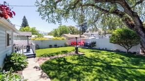 A backyard with a lawn, a patio area with outdoor furniture, and a white fence. - Vacations on Vine by Avantstay BBQ Yard + Patio Paso Robles Wine Country (Paso Robles)