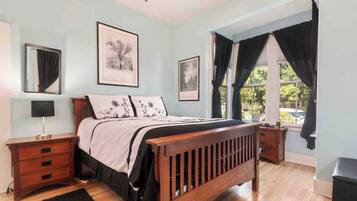 A bedroom with a wooden bed, a nightstand, a lamp, and two framed pictures on the wall.