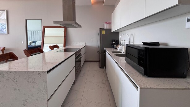 A modern kitchen with a marble countertop, stainless steel appliances, and a built-in oven. - Apartment in New Vallarta (Nayarit)