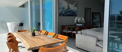 Een moderne eethoek met een houten tafel en stoelen, een bank en een groot raam.