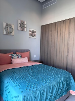Un dormitorio con una cama, almohadas, un armario de madera y decoración en la pared.