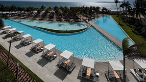 A resort pool with sunbathing areas and a view of the ocean. - Apartment in New Vallarta (Nayarit)