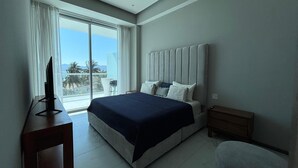 A modern hotel room with a large bed, a TV on a stand, a small table, and a chair. - Apartment in New Vallarta (Nayarit)