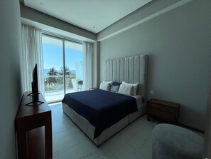 A modern hotel room with a large bed, a TV on a stand, a small table, and a chair. - Apartment in New Vallarta (Nayarit)