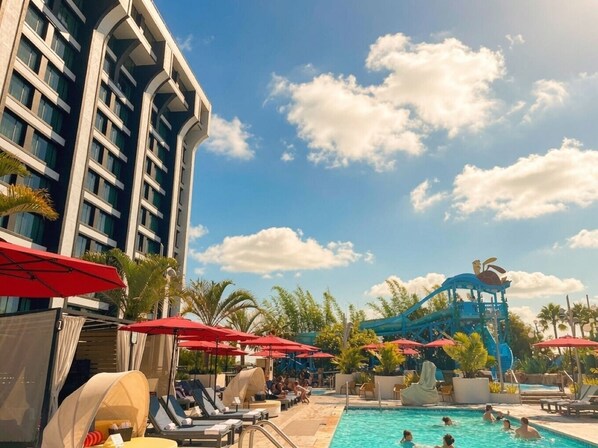 A hotel pool area with a water slide and lounge chairs.