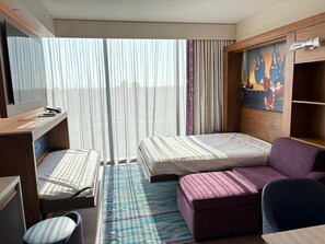 Una habitación de hotel con dos camas, un escritorio, una silla, un sofá y un cuadro en la pared.