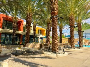 A courtyard with palm trees, outdoor seating, and a pool area.