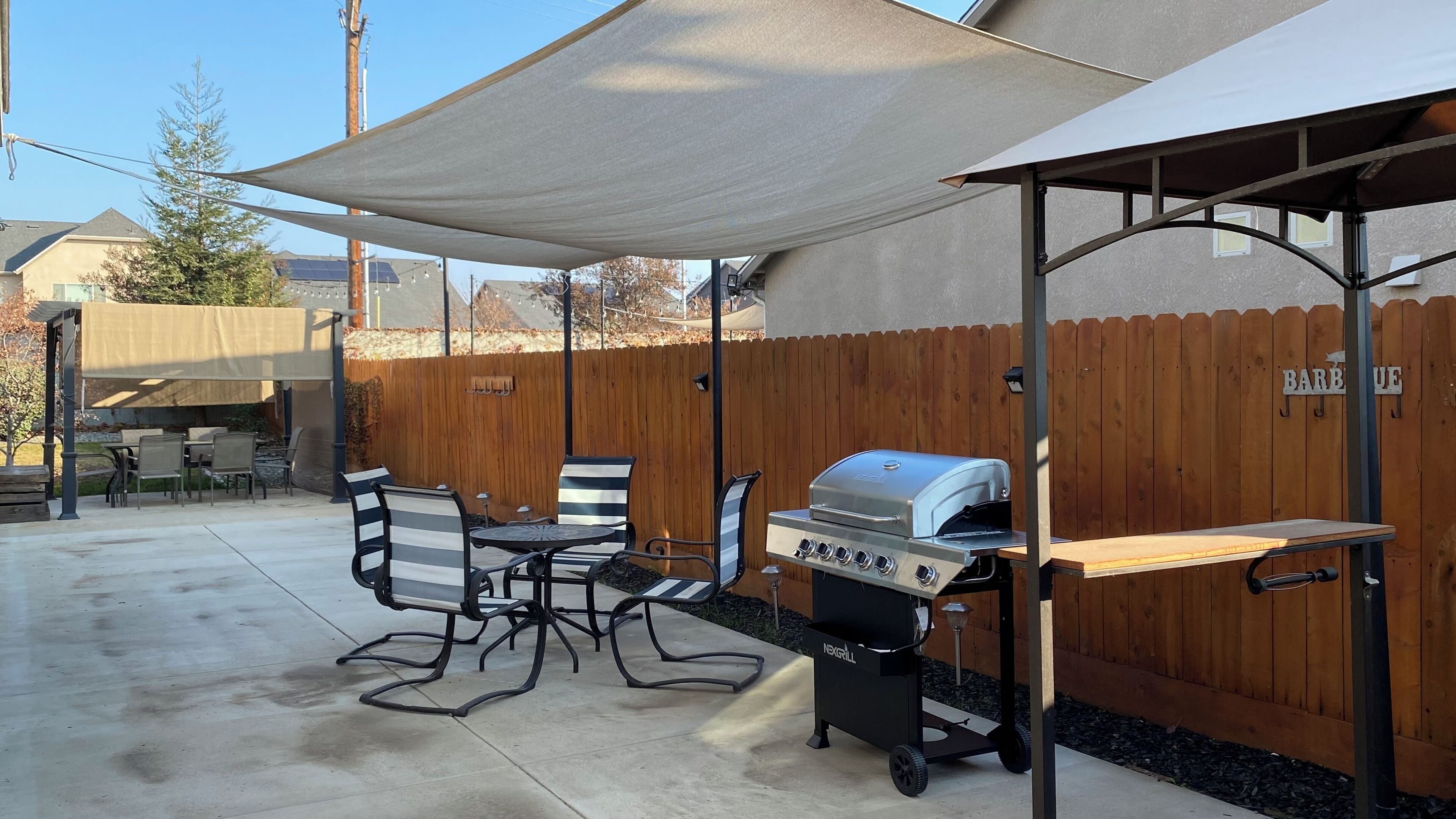 An outdoor patio with a grill, table, and chairs.