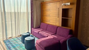 Una sala de estar con sofá, otomanas, un mueble aparador y una silla.