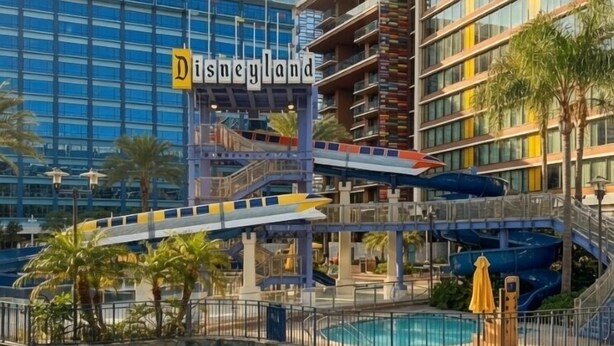 Un hotel con piscina, tobogán de agua y un cartel que dice 'Disneyland'.