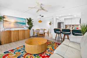 A modern living room with a round wooden coffee table, a sofa, and a dining area with chairs.