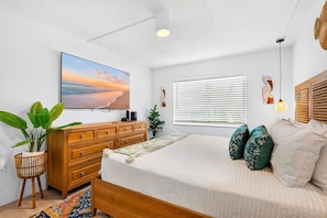 Un dormitorio con cama, cómoda de madera y un ventanal con persianas.