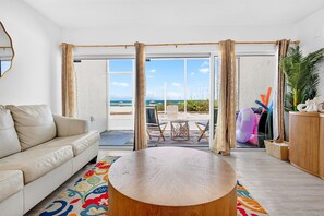 A modern living room with a beige sofa, a round wooden coffee table, and a colorful rug.